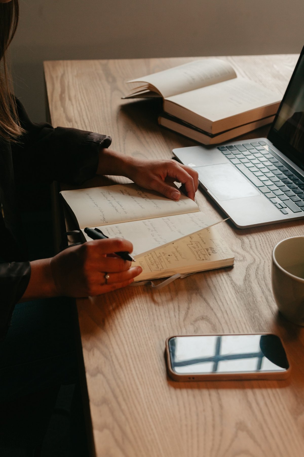 Notizbuch, Laptop und Tasse als ruhige Coaching-Arbeitssituation
